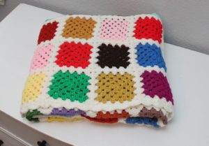 multicolored blocked afghan folded on a dresser