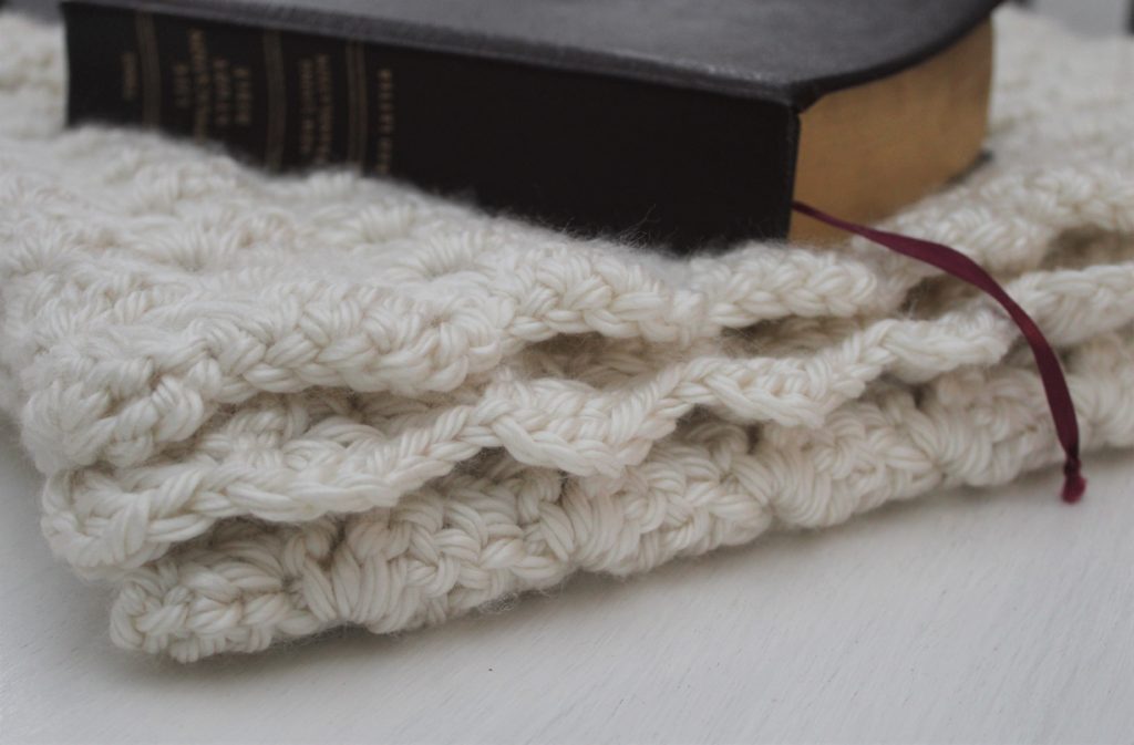 Bible laying on folded slanted double crocheted ivory shawl