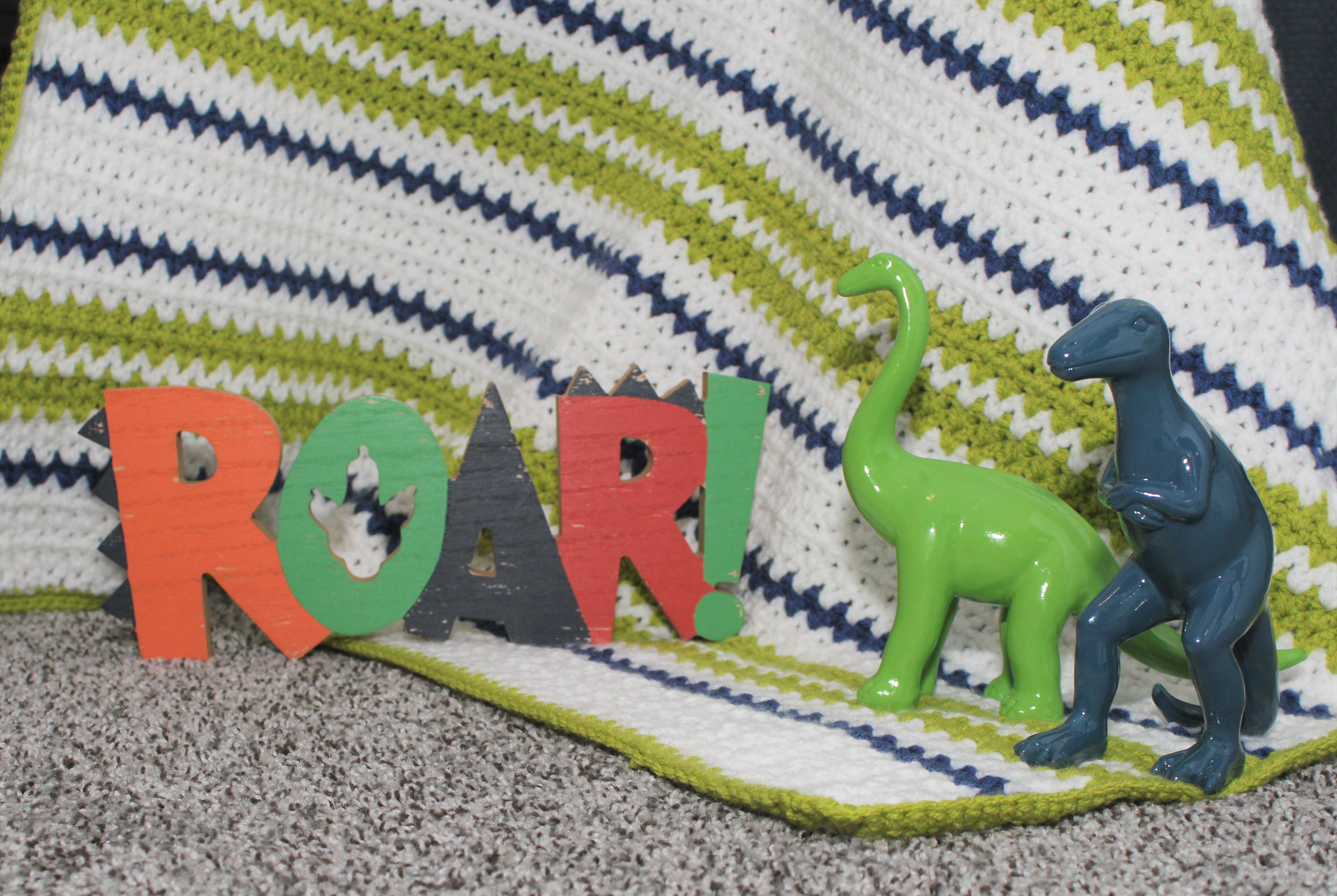 blue and green dinosaurs on blue and green afghan beside the word ROAR!