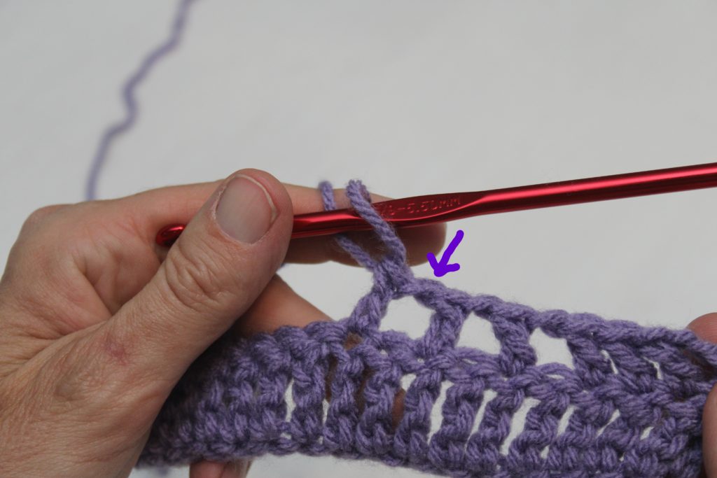 hands holding purple yarn showing a connecting chain
