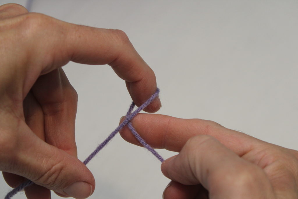 first step of making a slip knot, crossing yarn over