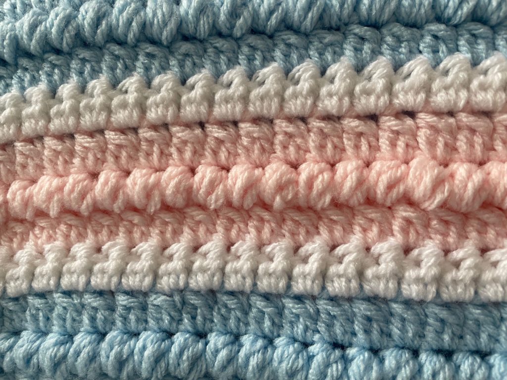crochet swatch of the cotton candy puff blanket  with pink, blue, and white using a double crochet cluster stitch and puff stitch