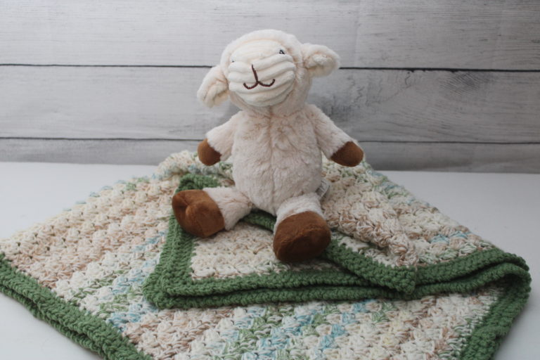folded green and ivory afghan with stuffed bunny