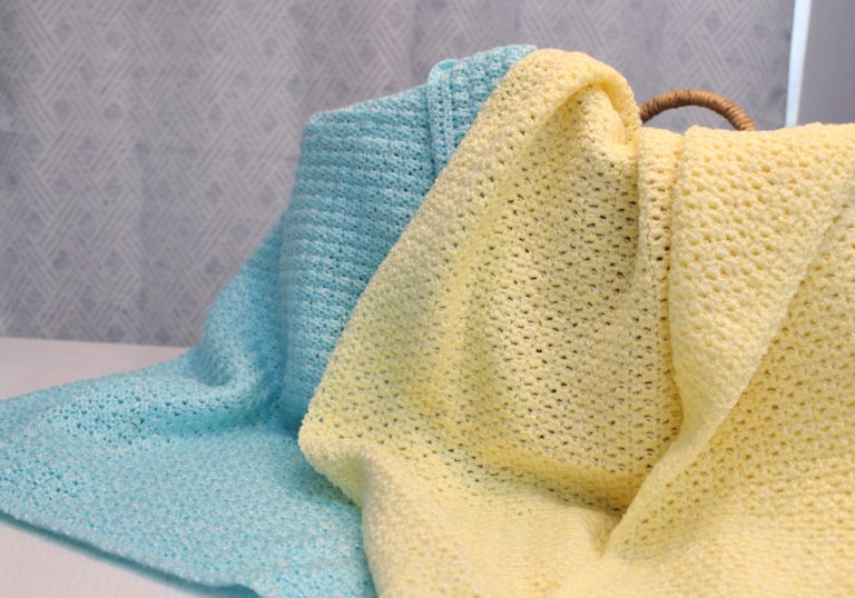 two afghans, one yellow and one blue, draped over a basket