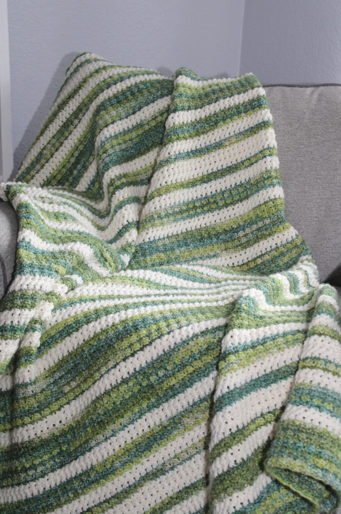 green and ivory striped afghan draped over a chair