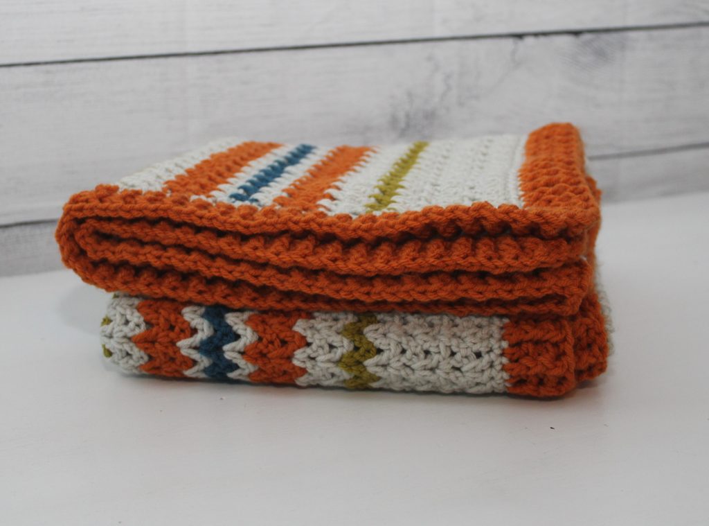 folded orange, grey, green and blue afghan on a table
