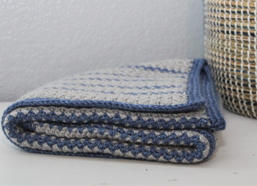 grey and blue striped afghan folded next to a basket