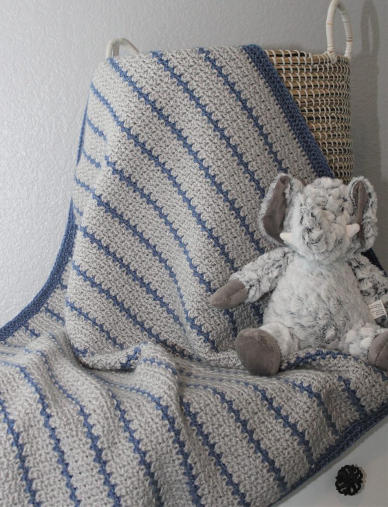 grey and blue striped crocheted afghan draped in basket with elephant