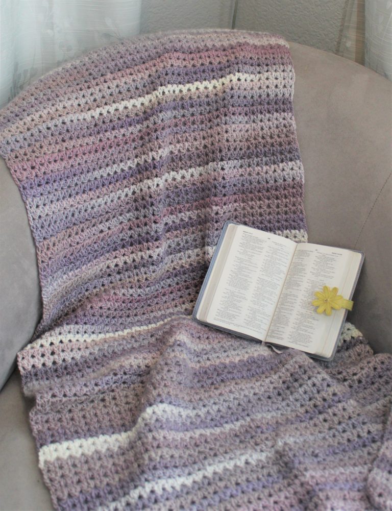grey and purple shawl draped over chair with open bible