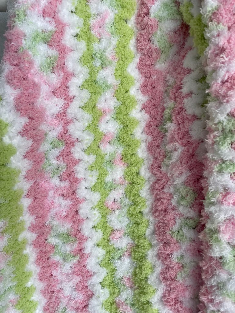 cozy and warm pipsqueak baby afghan in pink, green, and white stiped v-stitches up close