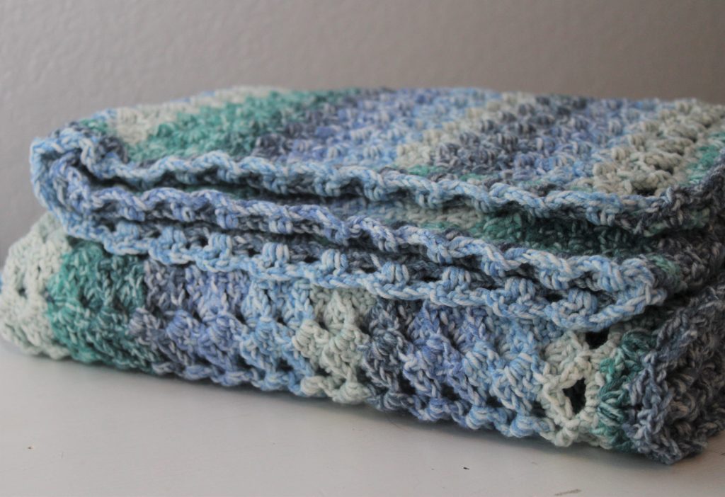 afghan in blues and greens folded on a table