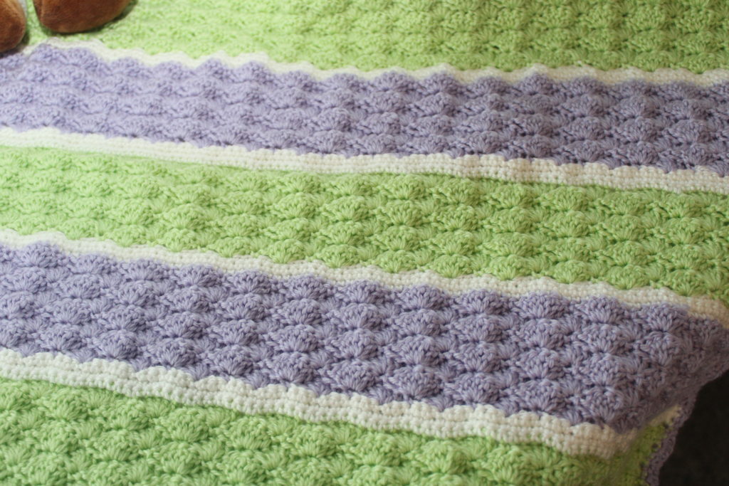 up close picture of the shell stitch in green, purple, and white'