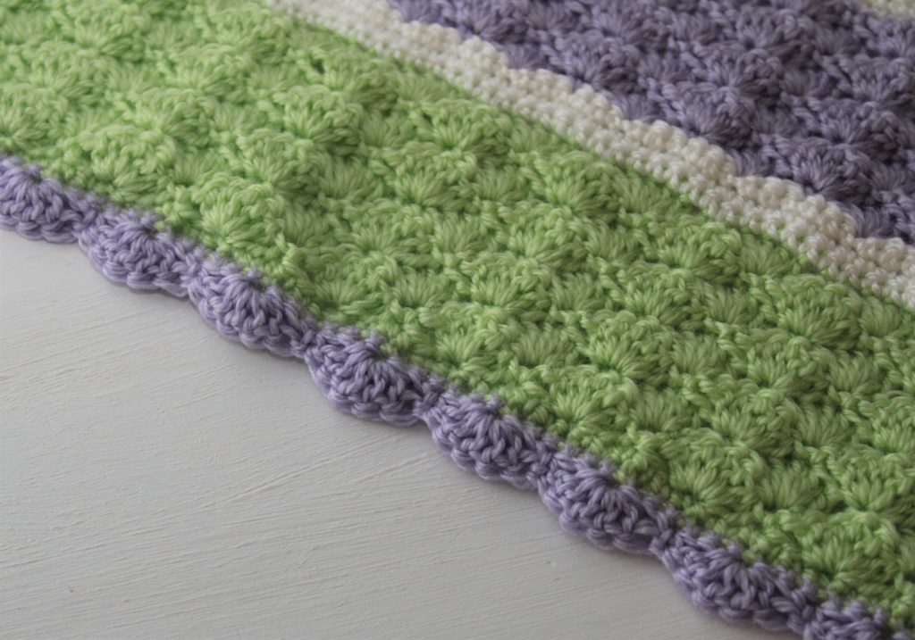close up of the border of the green, purple, and white blanket