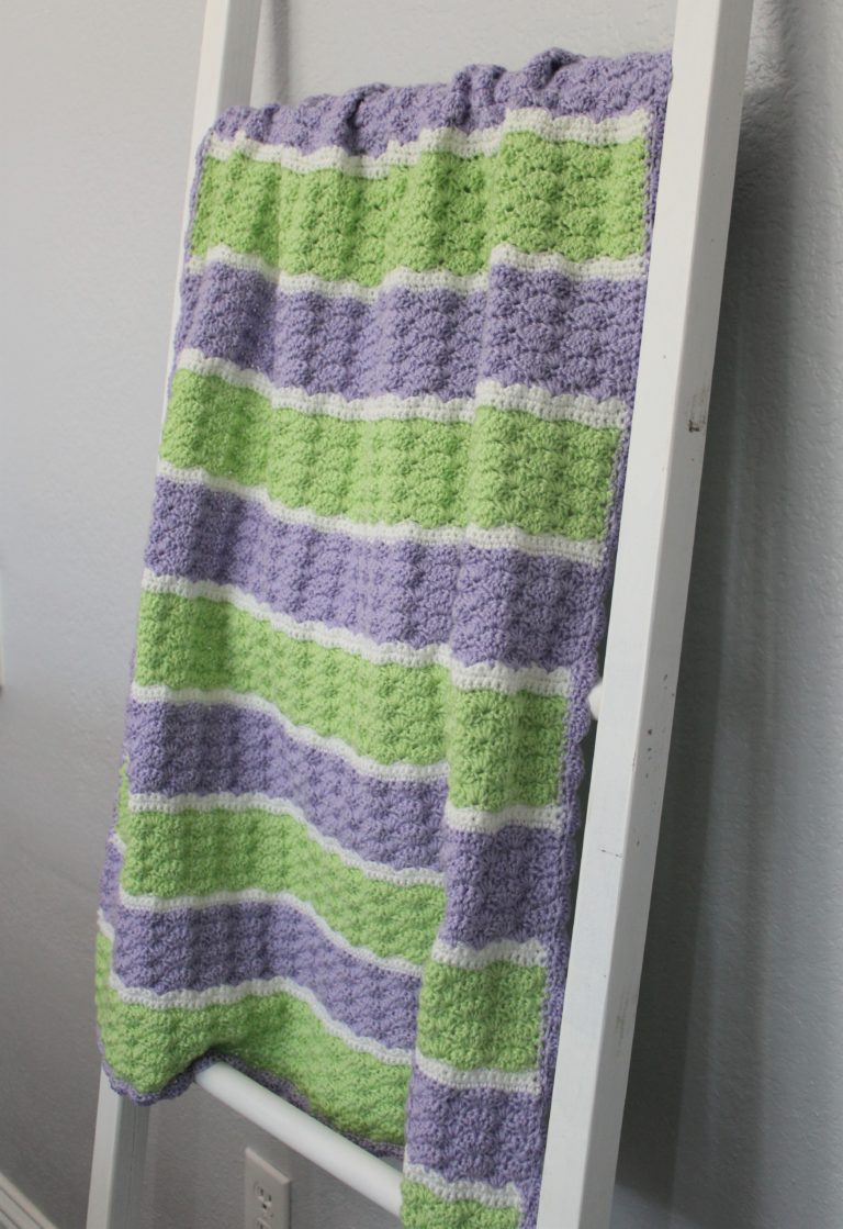 green, purple, and white stiped shell stich afghan on a blanket ladder