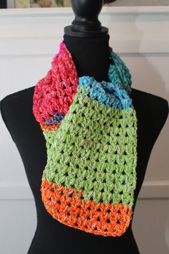 Happy Scarf on the neck of mannequin in colors of orange, blue, green and pinl=k