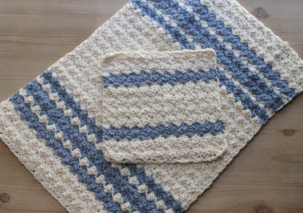 Sedge stitch farmhouse tea towel set in blue and white dish clothe laid on the blue and white striped tea towel