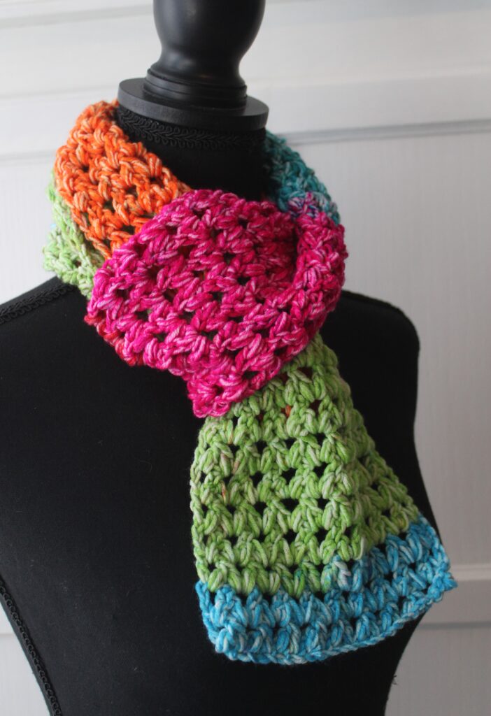  The Happy scarf; a forked cluster stitch scarf is bright colored crocheted scarf tied onto a mannequin